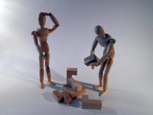 Dos figuras de madera manipulando bloques de madera