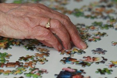 Manos de mujer mayor haciendo un puzzle